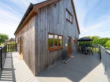 A wooden house with a deck and outdoor seating at James Ville Marina Lodge 7 in Brigg