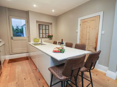 A kitchen with bar stools and a table at South Villa Sandsend near Whitby