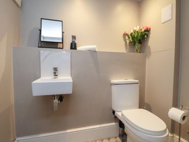 A bathroom with a sink, toilet, and flowers at South Villa Sandsend near Whitby