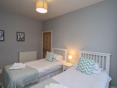 A bedroom with two beds and a lamp at South Villa in Sandsend near Whitby