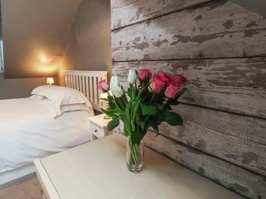 A bedroom with a vase of roses on a nightstand at South Villa in Sandsend near Whitby