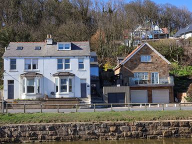 Two houses on a hillside with a road and fence at South Villa Sandsend near Whitby
