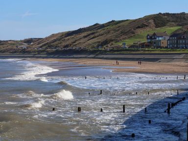 A beach with waves and houses along the shoreline at South Villa Sandsend near Whitby
