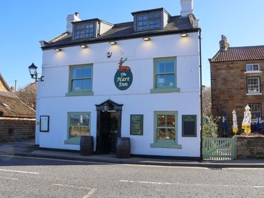 A pub exterior with signage and outdoor seating at The Hart Inn Sandsend near Whitby