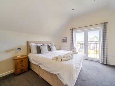 A bedroom with a large bed and a patio door opening to a balcony at James Ville Marina Lodge 9, Brigg