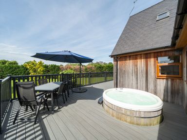 An outdoor deck with a hot tub and seating area at James Ville Marina Lodge 9 in Brigg