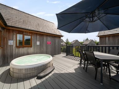 An outdoor deck with a hot tub and table at James Ville Marina Lodge 9 in Brigg