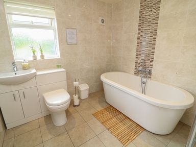 A bathroom with a bathtub, toilet, sink, and vanity unit at James Ville Marina Lodge 14 in Brigg