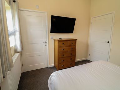 A bedroom with a television and dresser at James Ville Marina Lodge 14, Brigg