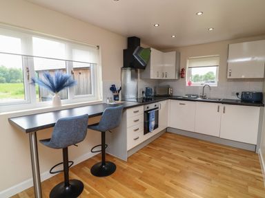 A kitchen with bar stools and kitchen appliances at James Ville Marina Lodge 21 in Brigg