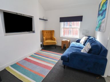 A living room with a blue sofa and yellow armchair at Apartment 3 in Scarborough