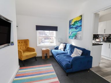 A living room with a blue sofa and yellow armchair at Apartment 3 in Scarborough