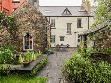 A garden with a stone building and table with chairs at The Secret Garden in Narberth