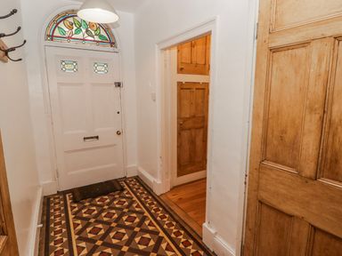 A hallway with a front door and stained glass window at The Secret Garden in Narberth