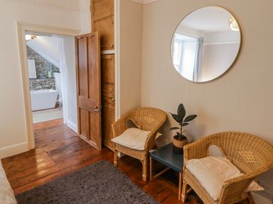 A bathroom with a bathtub and two chairs at The Secret Garden in Narberth