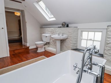A bathroom with a bathtub, toilet, and sink at The Secret Garden in Narberth