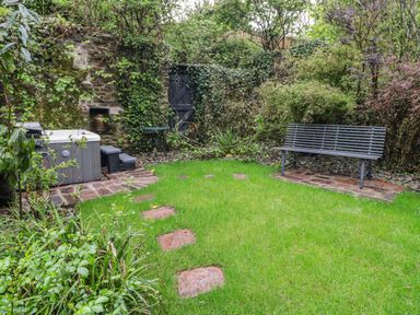 A garden with a hot tub and a bench at The Secret Garden in Narberth