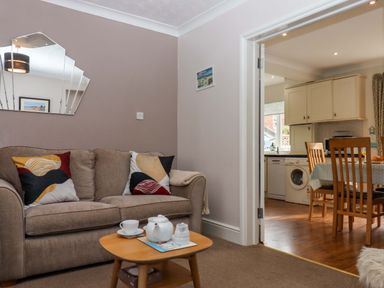 A living room with a sofa and coffee table leading to a kitchen at 16 Elmbank Gardens Paignton