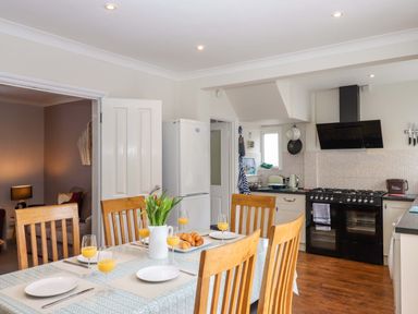 A kitchen with a dining table and wooden chairs at 16 Elmbank Gardens in Paignton
