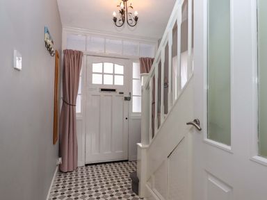 A hallway with a door and staircase at 16 Elmbank Gardens Paignton