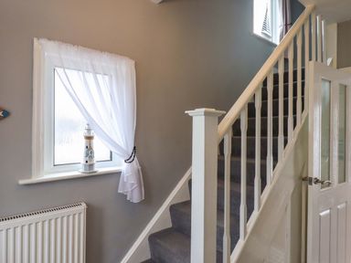 A hallway with stairs and a window at 16 Elmbank Gardens Paignton