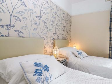 A bedroom with two beds and a floral wallpaper at 16 Elmbank Gardens Paignton