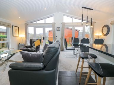 A living room with seating and dining area at Waters Edge Lodge Windermere