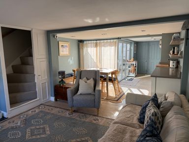 A living room with stairs, a sofa, and a kitchen counter at York Cottage Southwold
