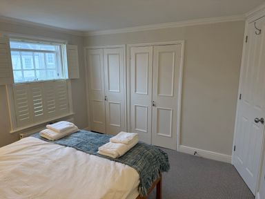 A bedroom with a bed and closet doors at York Cottage Southwold