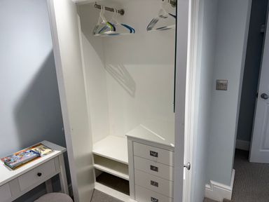 A wardrobe with hangers and drawers at York Cottage Southwold