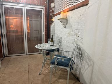 A table and two chairs with a wine bottle on the table at York Cottage in Southwold