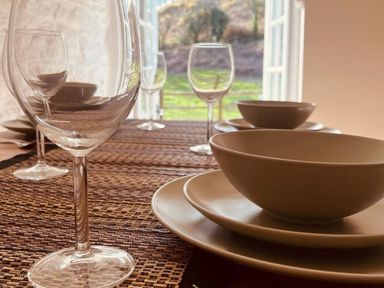 A dining table set with plates and glasses at Coach House near St Clears