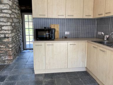 A kitchen with cabinets and a microwave at Coach House near St Clears