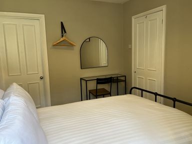 A bedroom with a bed, desk, chair, and mirror at Coach House near St Clears
