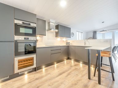 A kitchen with appliances and a stool at Sonnet 3 Spa in Carmarthen