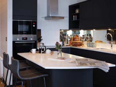 A kitchen with an island, coffee maker, and bar stools at Wilde Spa (Pet) in Carmarthen