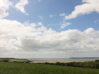 A view of water and grass under a cloudy sky at Radharc an Hook @ Estuary Bliss
