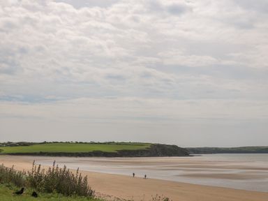 A beach with water and people walking at Radharc an Hook @ Estuary Bliss