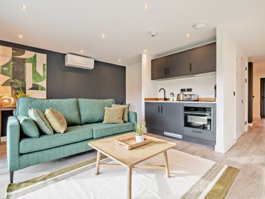A living room with a sofa and kitchenette at Arvor Studio 1.0 Bude