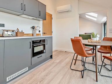 A kitchen with cabinets, microwave, toaster, and dining table at Whalesborough Penthouse 2.0 in Marhamchurch