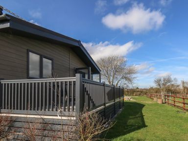 A house with a deck and fencing on a lawn at Grass Roots