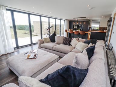 A living room with a sofa and telescope at The Joiners Cottage in Birling near Warkworth
