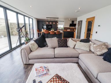 A living room with a sofa and telescope at The Joiners Cottage in Birling near Warkworth