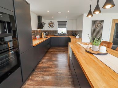 A kitchen with black cabinets and wood countertops at The Joiners Cottage in Birling near Warkworth