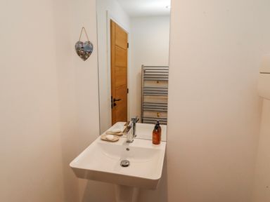 A bathroom with a sink and towel rack at The Joiners Cottage in Birling near Warkworth