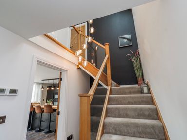 A staircase with lights and a wall art at The Joiners Cottage in Birling near Warkworth