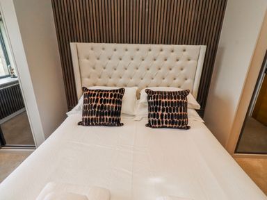 A bed with pillows and a headboard in a bedroom at The Joiners Cottage Birling near Warkworth