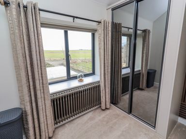 A bedroom with a window and mirror at The Joiners Cottage in Birling near Warkworth