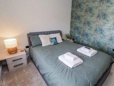 A bedroom with a bed and bedside table at The Joiners Cottage in Birling near Warkworth