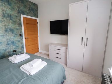 A bedroom with a bed and a wardrobe at The Joiners Cottage in Birling near Warkworth